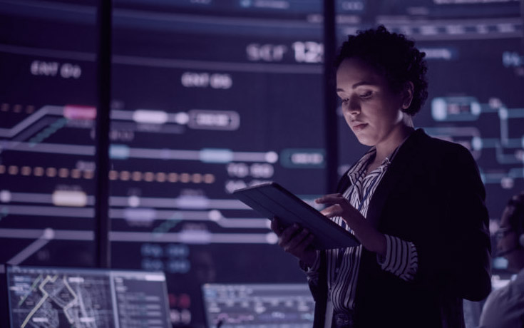 business woman looking at tablet in control room