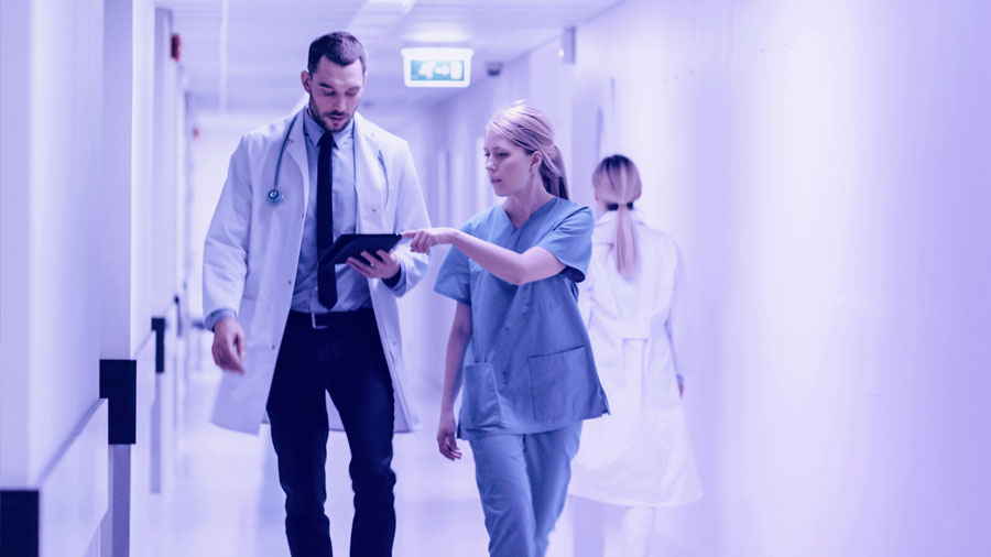 Doctors consult digital tablet in hospital hallway