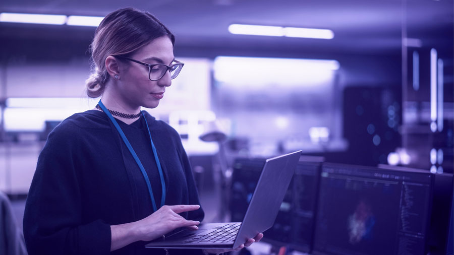 Female working holding laptop in a computer room