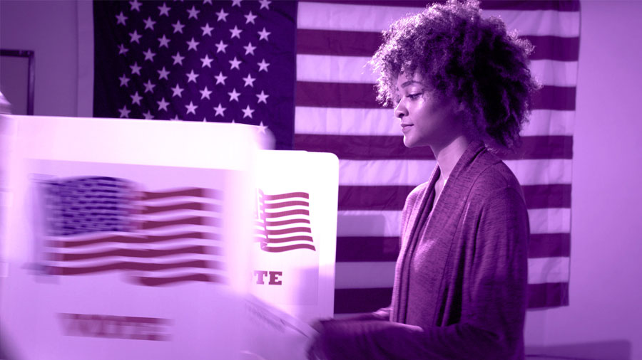 woman casting a vote in an election booth with US flag